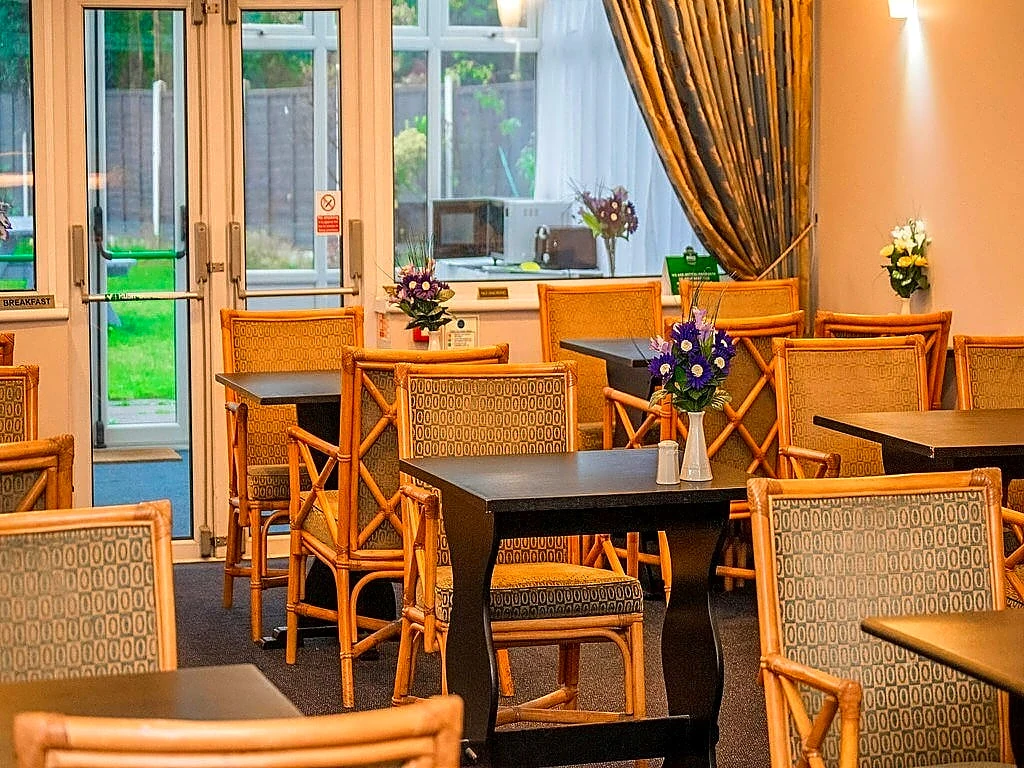 The bright breakfast room with tables laid for guests